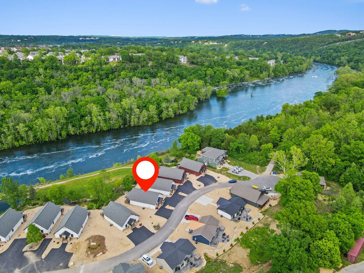 This image features a tranquil river bordered by lush greenery and a well-kept neighborhood. The scene suggests opportunities for boating, fishing, and walking along the waterfront, while also highlighting the sense of community and outdoor engagement.