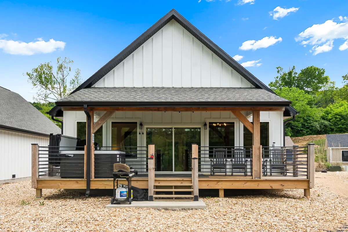 The exterior view showcases a welcoming front porch with large windows and a wooden deck, perfect for morning coffee or evening gatherings. The inviting space hints at shared moments, relaxation, and group gatherings.