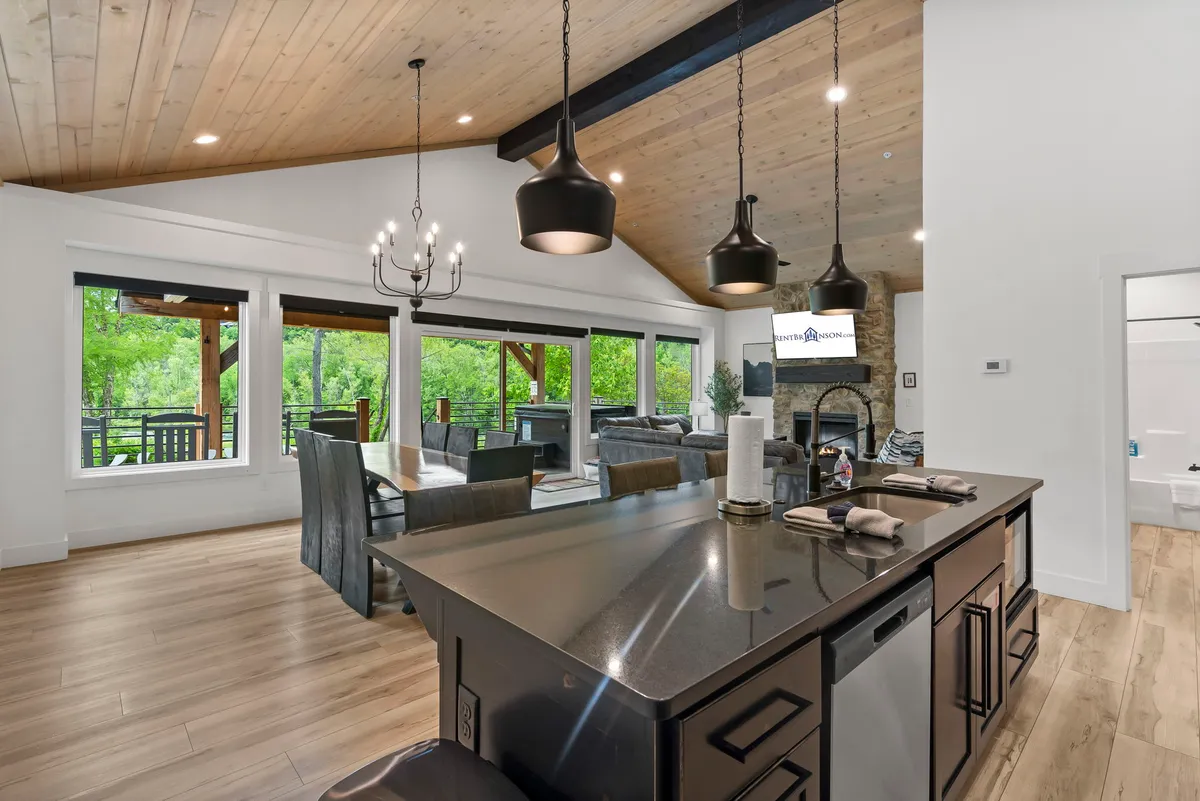 A bright, inviting kitchen and dining area with a kitchen island, a large dining table, and floor-to-ceiling windows that bring natural light and outdoor views inside. The space is perfect for cooking, sharing meals, and enjoying each other's company.