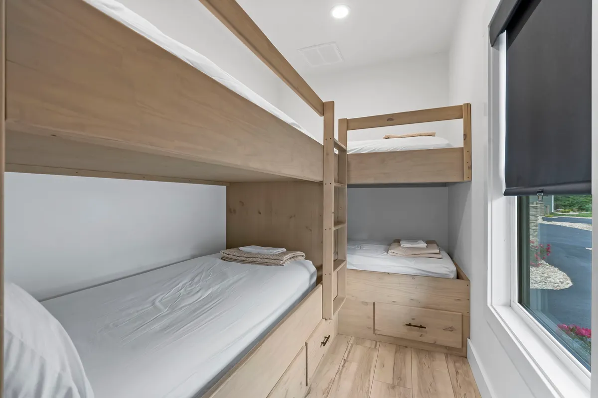 A dedicated bunk room with neatly made wooden bunk beds, inviting bedding, and a relaxed, playful atmosphere. The space is thoughtfully designed for children or young guests to unwind and bond.